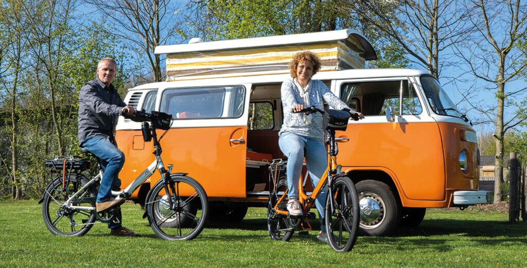 elektrische-vouwfiets-lacros-landing2 Een man en vrouw op een elektrische vouwfiets voor hun camper.
